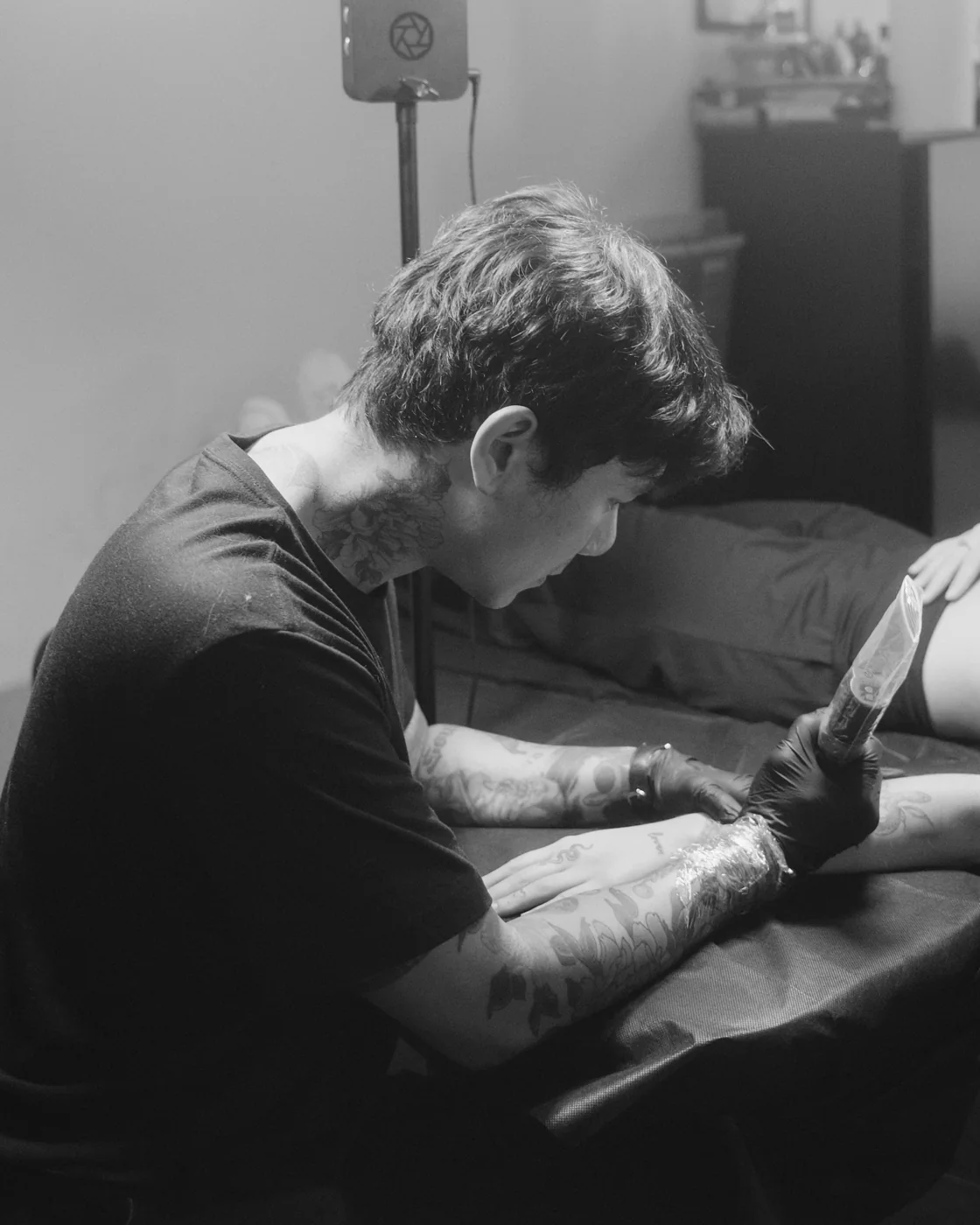 The artist at work, tattooing a client's arm