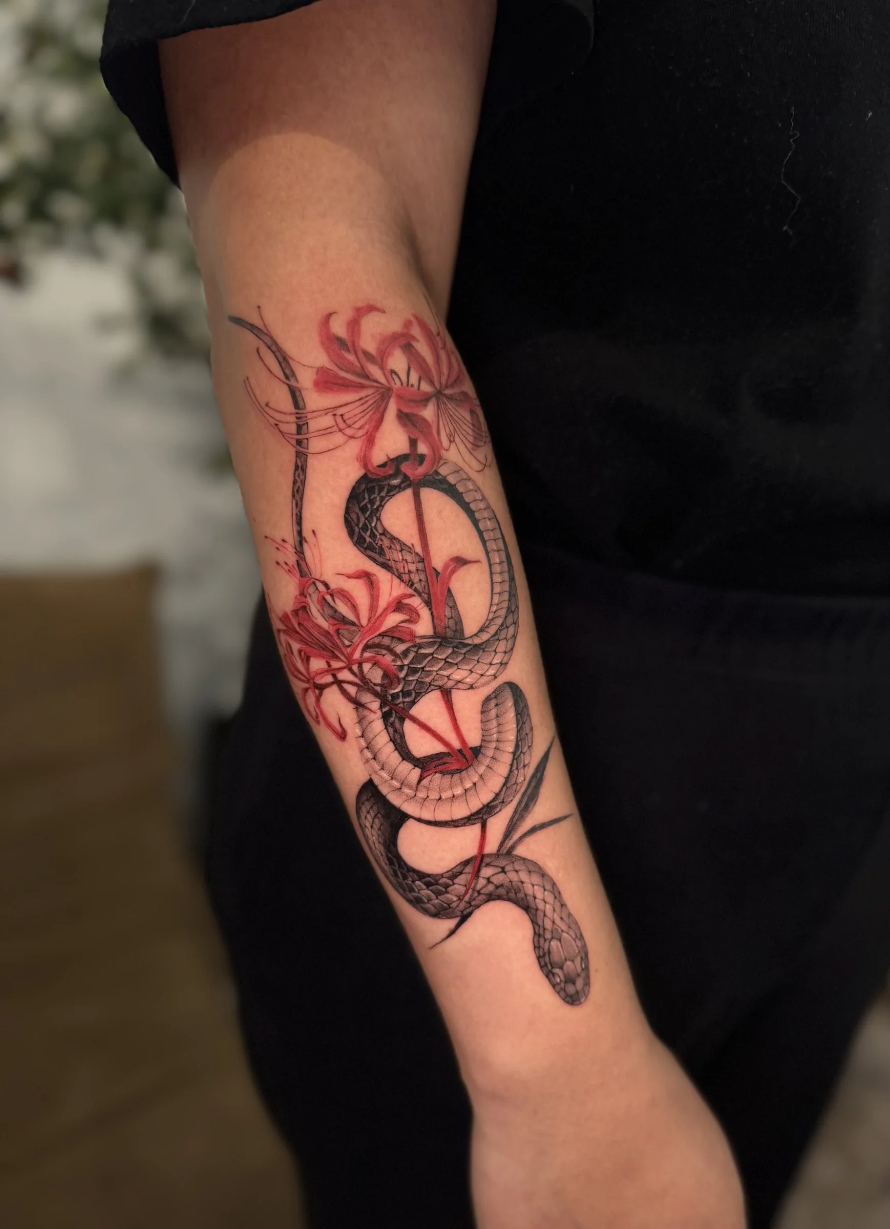Snake with red spider lilies on a forearm