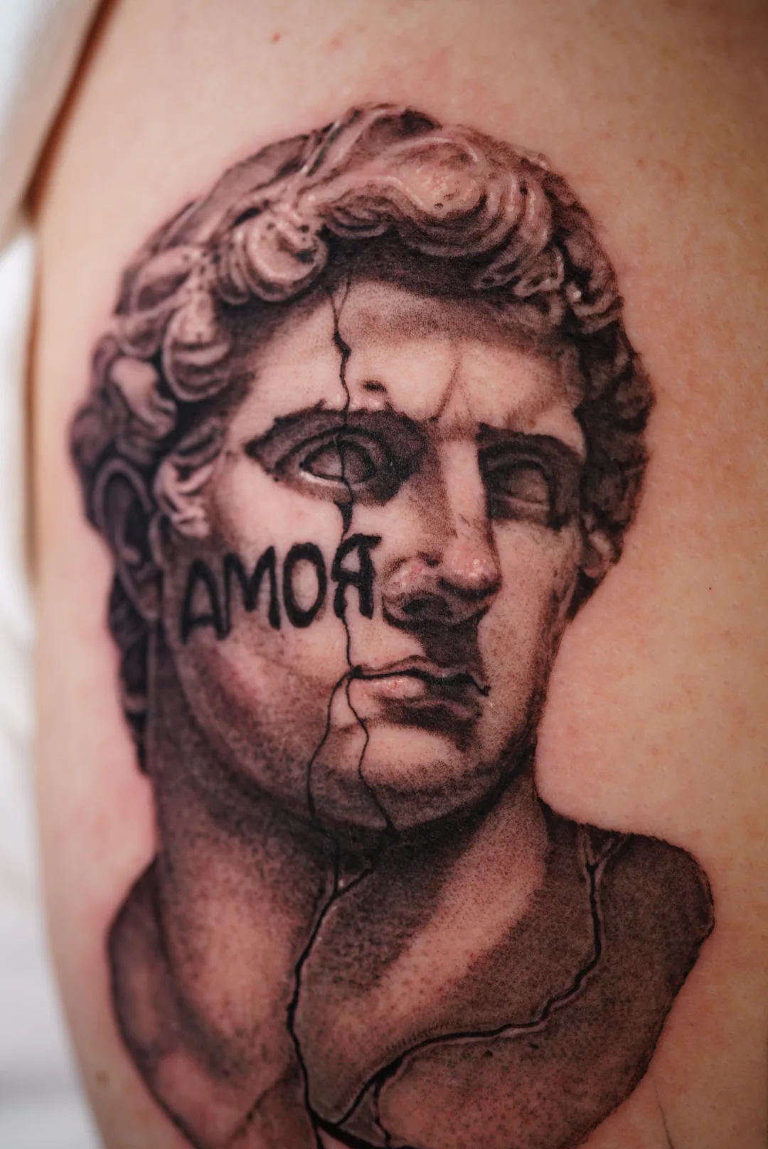 Classical marble bust tattoo with the word AMOR across the face